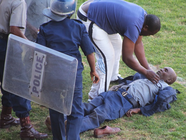 A samaritan attends to an injured Police Officer at Barbourfields Stadium in Bulawayo yesterday.